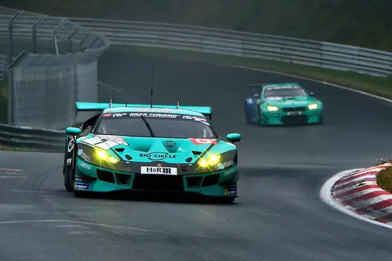 racen op de Nurburgring in de Eifel. twee racewagens rijden op het bochtige circuit vlak langs de hekken.