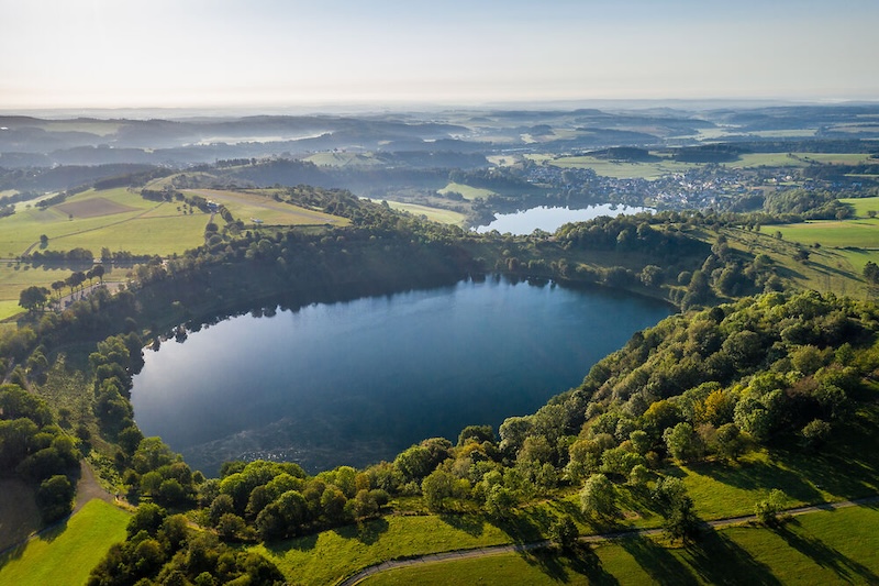Een maare in de vulkaaneicel vanuit de lucht gezien, met een wandelroute er omheen.