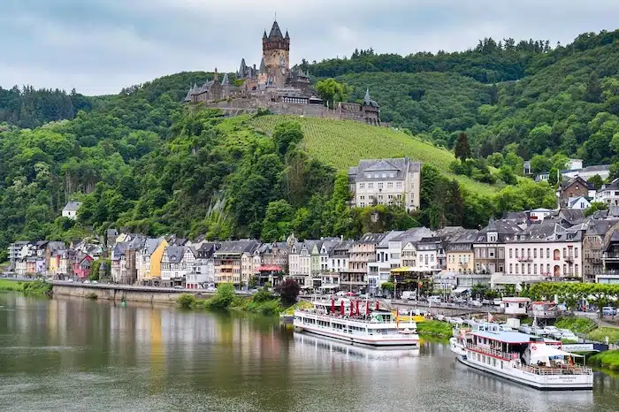 Cochem aan de moezel met rondvaartboten die aangemeerd liggen aan de kade van het stadje. hoog op de heuvels is de burcht te zien