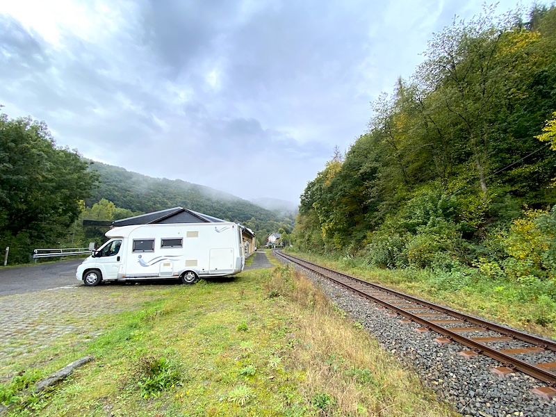parkeerplaats en camperplaats in Monreal in de Eifel. Een camper staat geparkeerd op een mooie rustige plek bij het spoor. de omgeving is heuvelachtig en groene natuur.