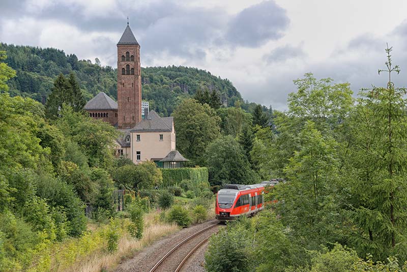 gerolstein trein openbaar vervoer. spoor met trein rijdt door het groene heuvellandschap langs een toren in de stad