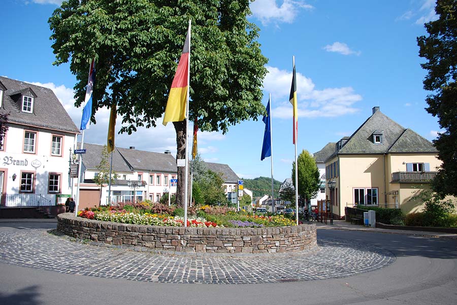 De binnenkomst in Manderscheid. De rotonde met vlaggen.