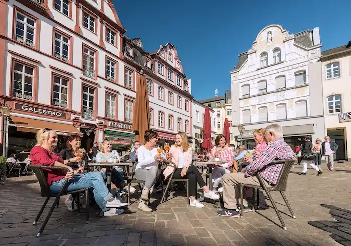 Terrasje in de Altstadt van Koblenz, met mensen die genieten van eten en drinken tussen de sfeervolle oude gebouwen.