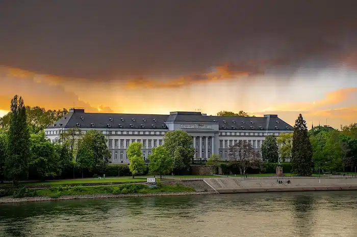 Uitzicht op het Kurfürstliches Schloss in Koblenz vanaf de Rijn, een historisch paleis met een elegante gevel en groene parklandschappen.