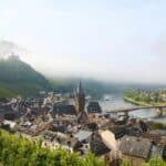 Bernkastel-Kues aan de Moezel. Uitzicht op de twee delen van de stad waar de Moezel tussen stroomt met groene, glooiende wijnheuvels op de achtergrond.
