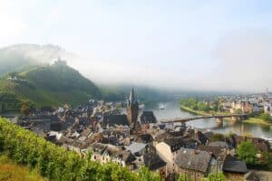 Bernkastel-Kues aan de Moezel. Uitzicht op de twee delen van de stad waar de Moezel tussen stroomt met groene, glooiende wijnheuvels op de achtergrond.