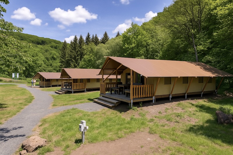 glamping in de Eifel. 3 safaritenten aan een bosrand met een pad ervoor. op de achtergrond groene heuvels.