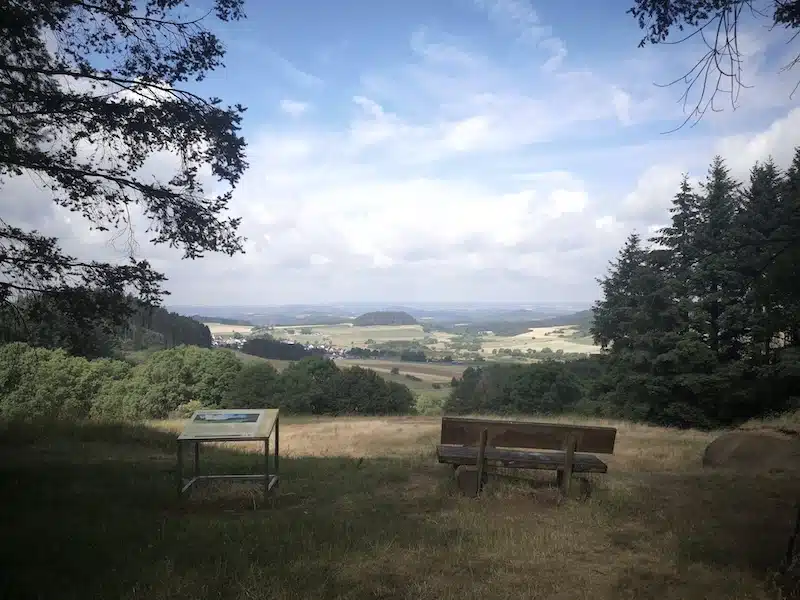 uitzicht over het eifel landschap met op de voorgrond bankjes en een infobord