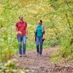 wandelen op het HeimatSpur Achtsamkeits-Pfad Kleine Kyll. man en vrouw wandelen op een pad vol met bladeren in het mooie groene bos in de eifel. foto © Florian Trykowski / Rheinland-Pfalz Tourismus GmbH