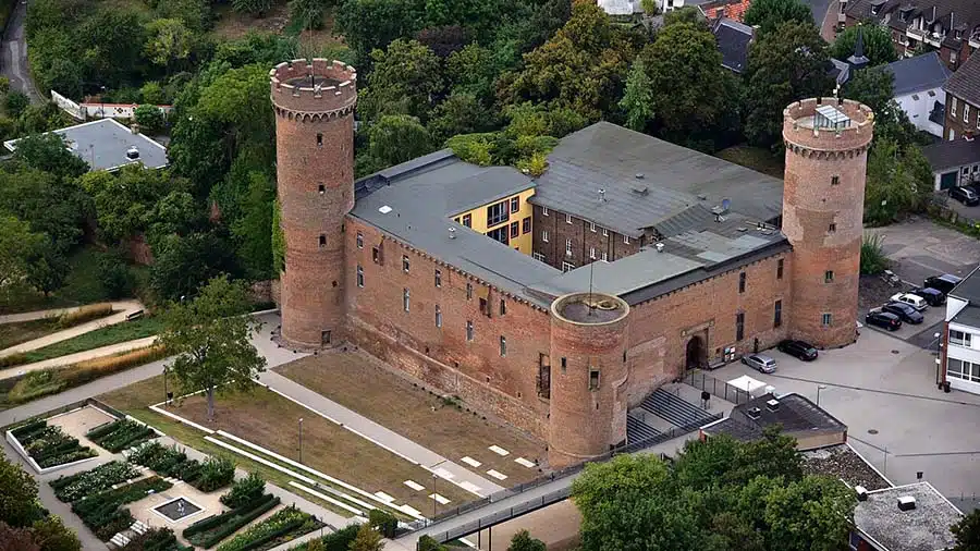 luchtfoto van de burcht in Zülpich. Je ziet het vierkante complex met de torens op de hoeken. er omheen zijn delen van de stad zichtbaar