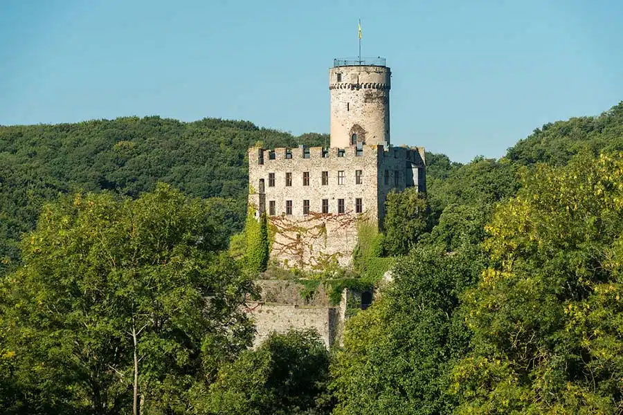 zichtbaar is burg Pyrmont op de wandelroute het traumpfad parmanter felsensteig. het kasteel op de groene heuvel met een blauwe zomerse lucht op de achtergrond
