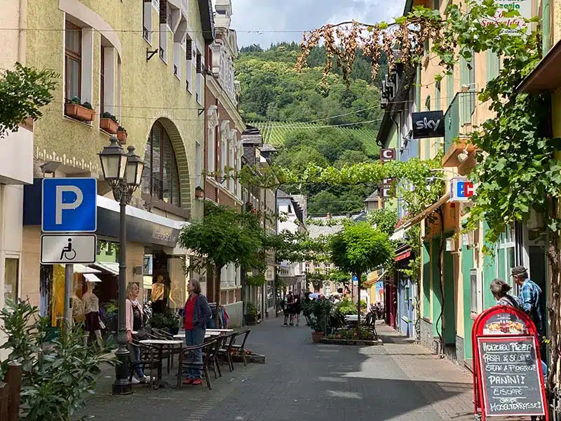 winkelstraatje met terrasjes in Traben-Trarbach. gezellig smal straatje met winkels en boompjes en aan het einde van de straat is de berghelling zichtbaar met de wijnranken erop